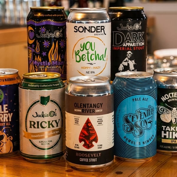 Assortment of craft beer cans from various breweries displayed on a wooden bar top.