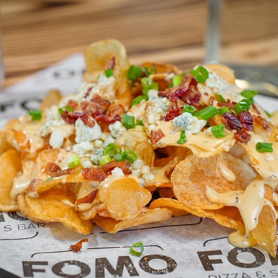 Crispy potato chips loaded with melted cheese, bacon bits, blue cheese crumbles, and green onions.